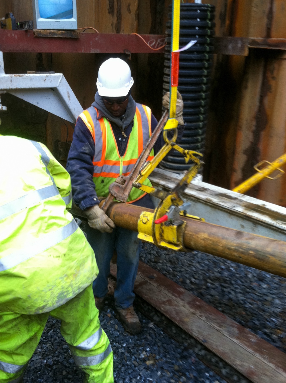 Worker operating pipe connection in shoring pit